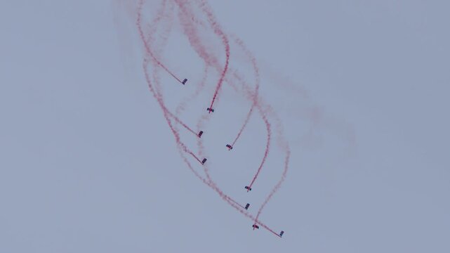 Parachute team floating to the ground with red smoke trails
