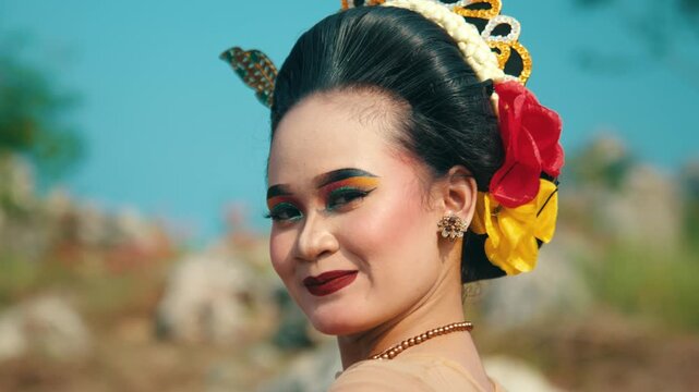 A charming close-up of a traditional dancer glancing back over her shoulder with a flirtatious and sweet smile, highlighting her beauty and makeup.