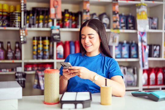 Smiling latin woman scanning auto parts with smartphone in a retail store