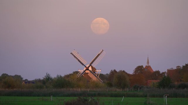Full moon over a traditional windmill in the Dutch countryside. Groningen, the Netherlands.