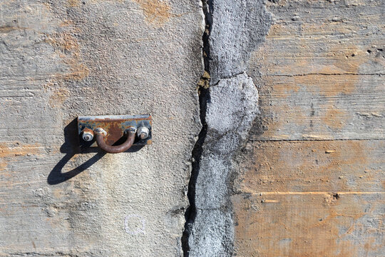 Concrete dam wall showing crack and metal fixture