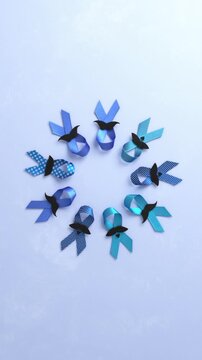 Blue november awareness concept. Various blue ribbons with black paper mustaches rotating in a circle against a light blue textured background