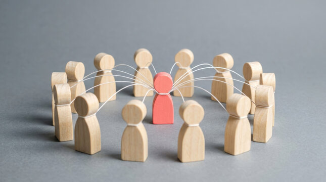 Pink wooden figurine tied with white cords to surrounding circle of people illustrates complex social ties and network dependency.