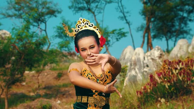 Footage of a female dancer executing a specific hand movement that looks like a defensive stance or a complex mudra, part of a traditional Javanese dance.
