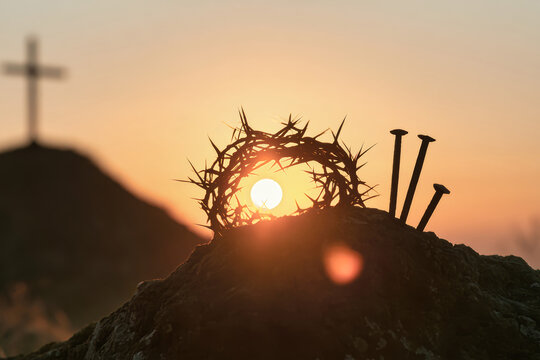 A crown of thorns and three nails sit on a rock as the sun sets. A cross is visible in the background. The scene captures a moment of quiet reflection