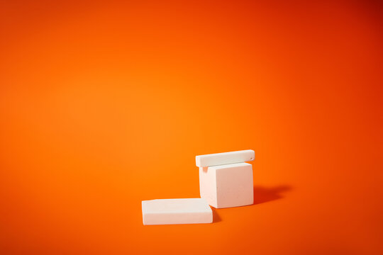 Minimalist White Geometric Podium Display on Vibrant Orange Background