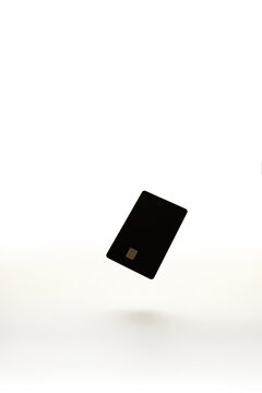 Black Blank Credit Card Floating in Midair on White Background, blurred, soft focus 
