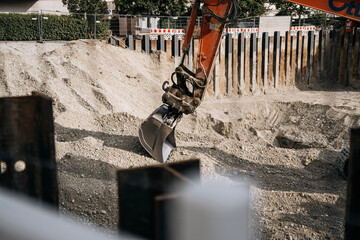 Excavator digging a foundation pit at an urban construction site, heavy machinery working behind temporary sheet piling © Natalia Schuchardt