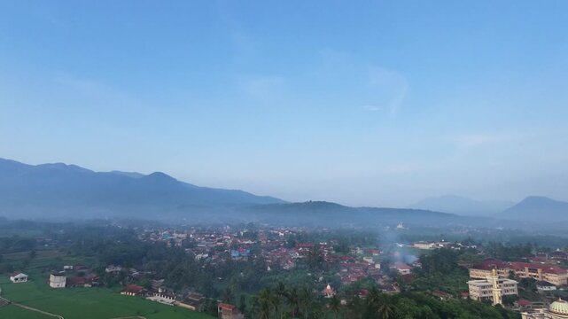 An aerial view captured by a drone showing mountains and settlements shrouded in cool morning fog in the Garut region of Indonesia