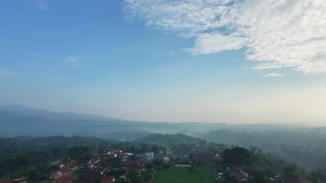 An aerial view captured by a drone showing mountains and settlements shrouded in cool morning fog in the Garut region of Indonesia