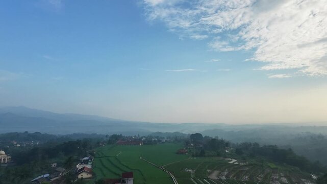 An aerial view captured by a drone showing mountains and settlements shrouded in cool morning fog in the Garut region of Indonesia