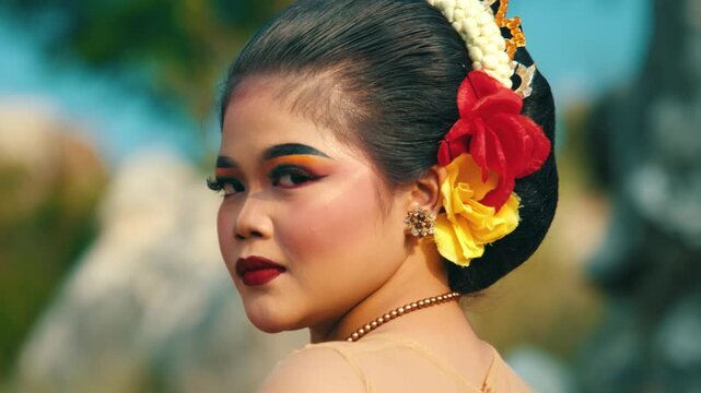 A dramatic over-the-shoulder shot of a traditional bride or dancer looking back with an intense gaze, focusing on her elaborate hair bun.