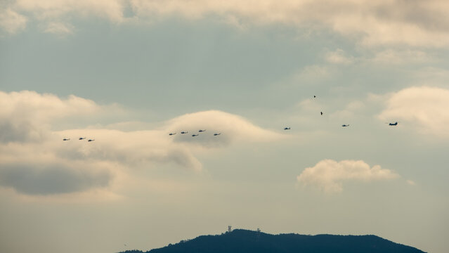 Japan Ground Self Defense Force Helicopters Flying in Formation over Mountainous Landscape Under Cloudy Sky