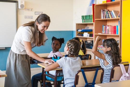 Teacher interacting with diverse elementary school students learning in a modern classroom environment, fostering education and growth