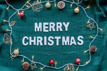 Obraz premium Merry Christmas greeting on green knit background with festive decor