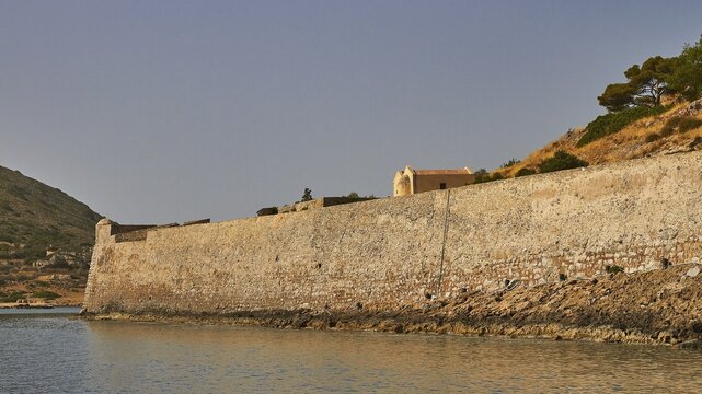 Long, old stone wall along the coastline, surrounded by a hill and calm sea, Venetian Sea Fortress, Leper Island, Spinalonga, Elounda Bay, Mirabello Bay, East Crete, Crete, Greek Islands, Greece