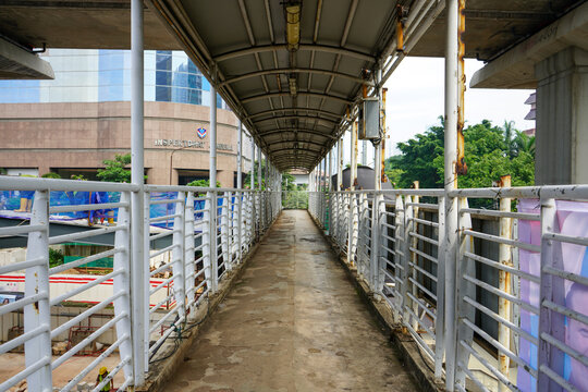 Pedestrian skywalk bridge with white railings and roof structure in Kuningan business district, Jakarta, Indonesia. Modern urban public infrastructure and city transit walkways concept background.