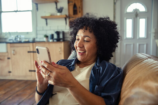 Smiling woman using smartphone on sofa at home