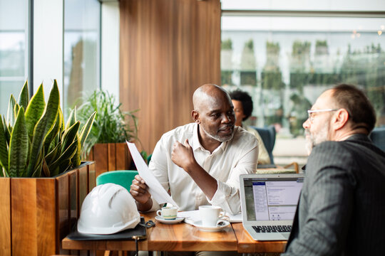 Colleagues discuss project paperwork in a cafe
