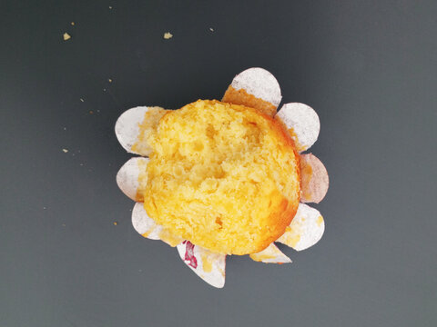 Delicious yellow muffin sponge cake in paper cup on dark background