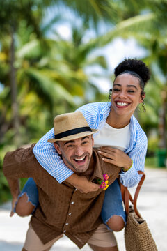 Romantic young couple enjoying a piggyback ride during their tropical honeymoon