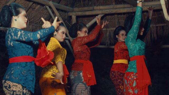 Side profile shot capturing a row of dancers in colorful ethnic wear maintaining a low stance (mendak) and posture during a rehearsal.