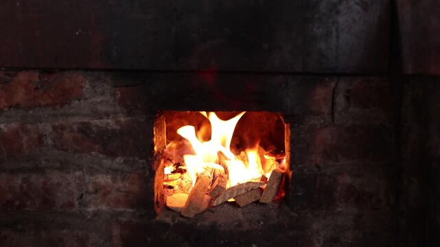 Burning Wood Logs in a Small Brick Stove with Bright Orange Flames