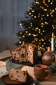 Festive Christmas eve dinner, traditional holiday table setting in rustic style, homemade Panettone bread on table, blurred Christmas tree lights on background