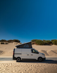 White camper van with pop top in sand dunes copy space © Paolo Corazza