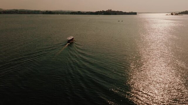 Aerial view of a small boat traveling across the calm waters of Lake Peten Itza towards the historic Island of Flores, Peten Department, Guatemala.