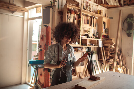 Woman waving on video call in woodworking shop