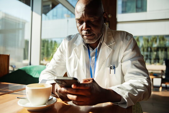Doctor checking smartphone during coffee break in cafe