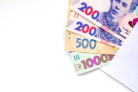Ukrainian hryvnia banknotes peeking out of a white envelope on a clean background