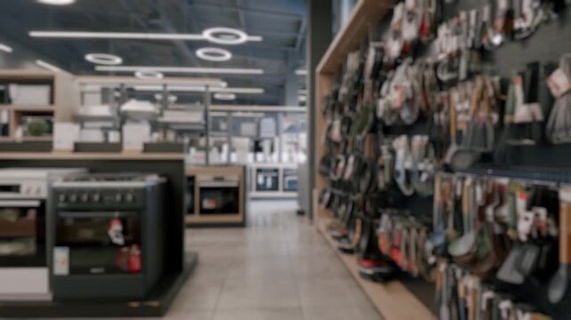 Defocused view of an aisle in a large home appliance and electronics store, showcasing a wide variety of kitchen equipment like ovens, stovetops, and cookware on display shelves for sale