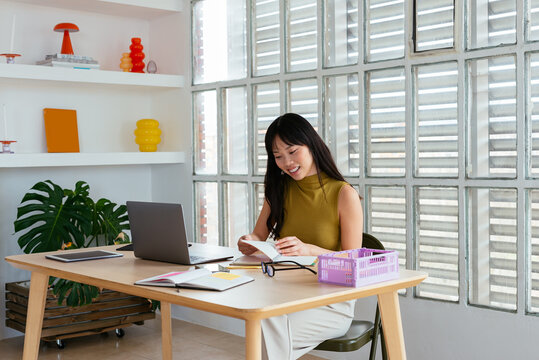 Beautiful young woman reading notes at modern workspace