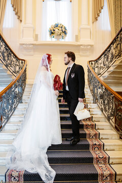 A man and a woman stand on the stairs in wedding attire