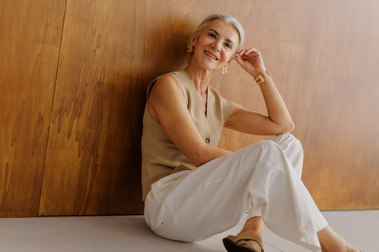 Senior woman sitting smiling displaying elegant jewelry