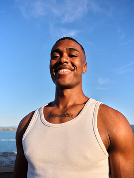 Young African American man smiling outdoors under blue sky