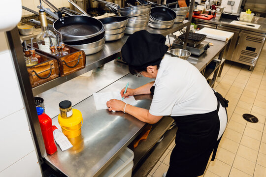 Kitchen Worker Writing Notes at Workstation