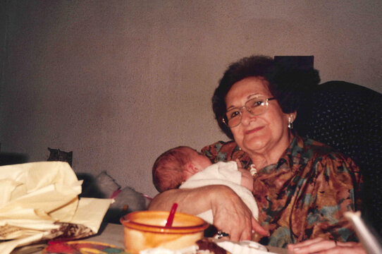 Woman Holding a Newborn Baby at a Family Gathering
