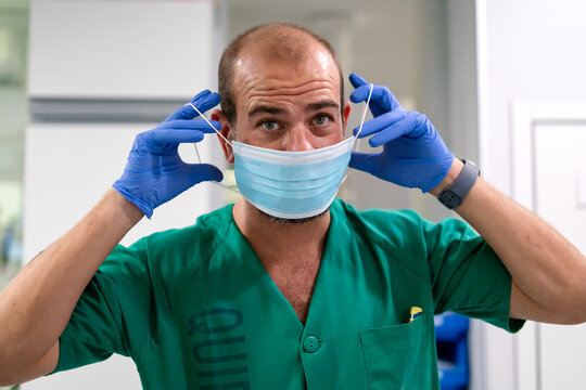 Medical professional wearing blue gloves putting on face mask