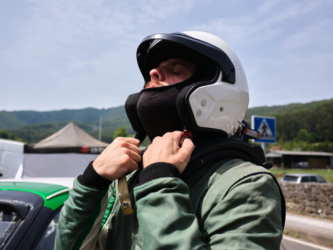 Rally driver preparing for race adjusting helmet