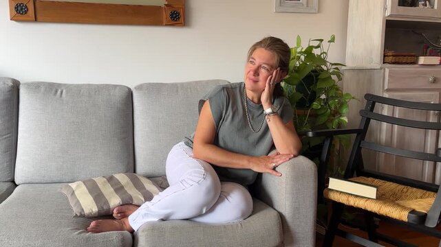 Calm and beautiful woman enjoying a peaceful and relaxing moment while sitting on a sofa at home