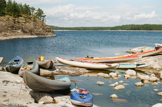 Kayaks and Canoes on Rocky Shore by Blue Water in Nature