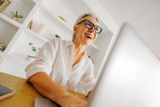 Senior woman working on laptop, experiencing joy and connection