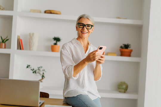 Senior woman holding smartphone smiling at camera