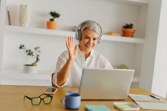 Happy senior woman waving during online video call
