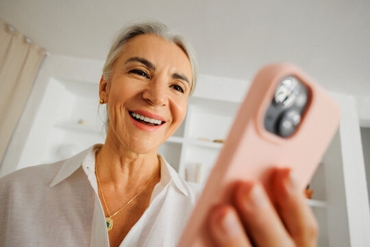 Happy senior woman enjoying smartphone video call at home