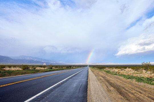 Rainbow stretching into the sky from the end of the highway