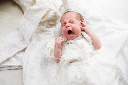 Baby Cries on White Blanket in Indoor Setting During Daytime